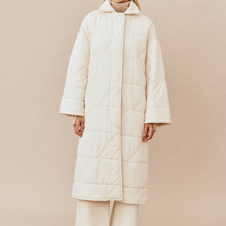 Model wearing the Australian luxury fashion designer GINGER & SMARTS' cream Sterling Quilted Coat featuring quilt detailing, lightweight design and is knee length.