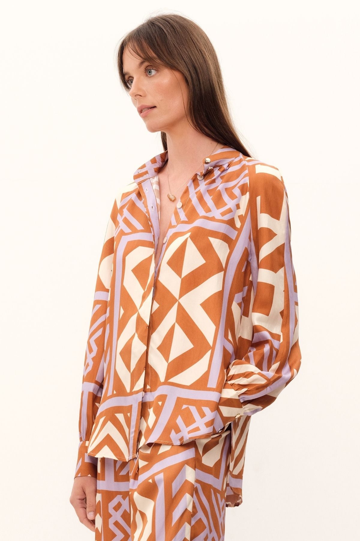 The House of Mirrors Blouse by GINGER & SMART has a bold geometric print in shades of crème, lilac, and tan. It includes a mandarin-style collar, concealed front placket, and full raglan sleeves with cuffs. Made with luxurious silk twill.