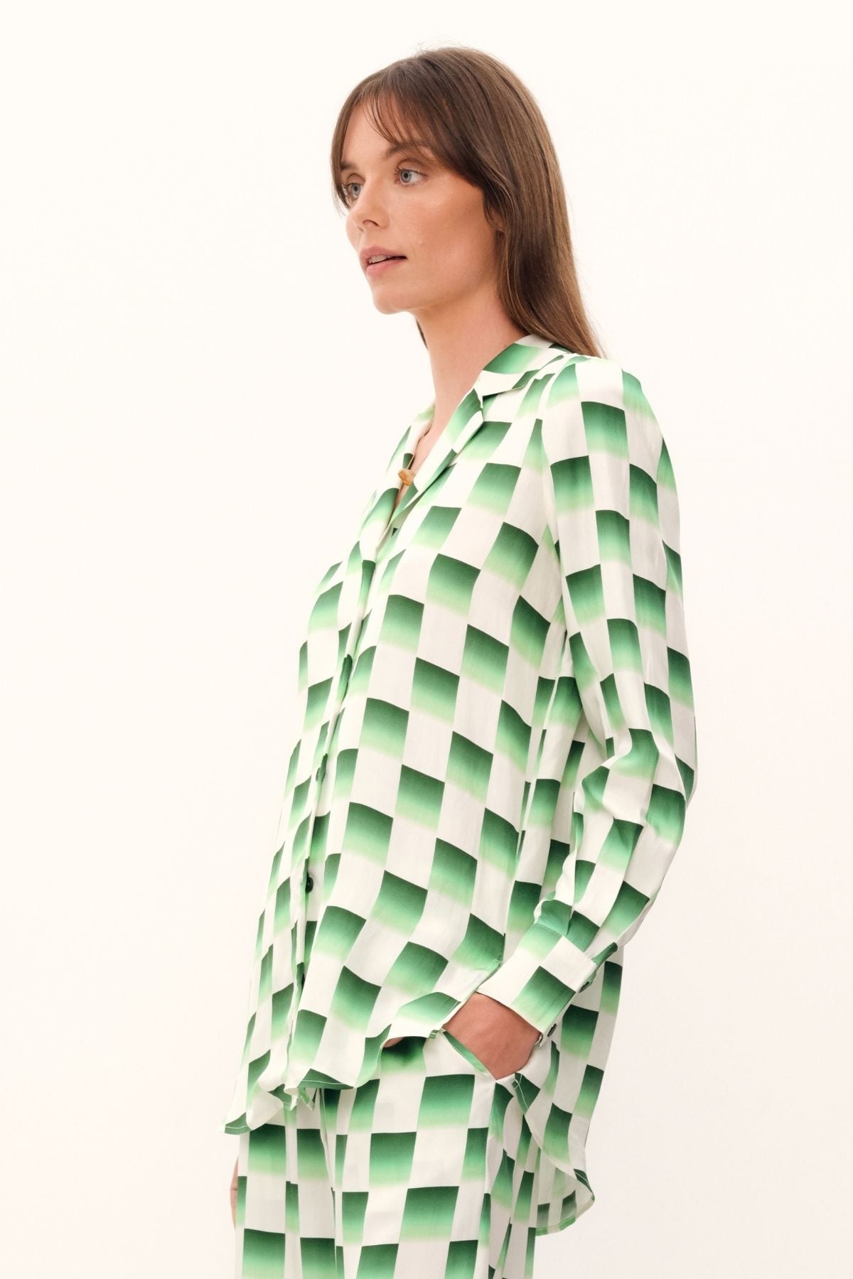 The Odyssey Blouse by GINGER & SMART is a luxurious silk twill with a checkerboard print in deep forest green and crisp white. It has a relaxed longline fit, straight hem, and GINGER & SMART logo Corozo nut buttons along the front.