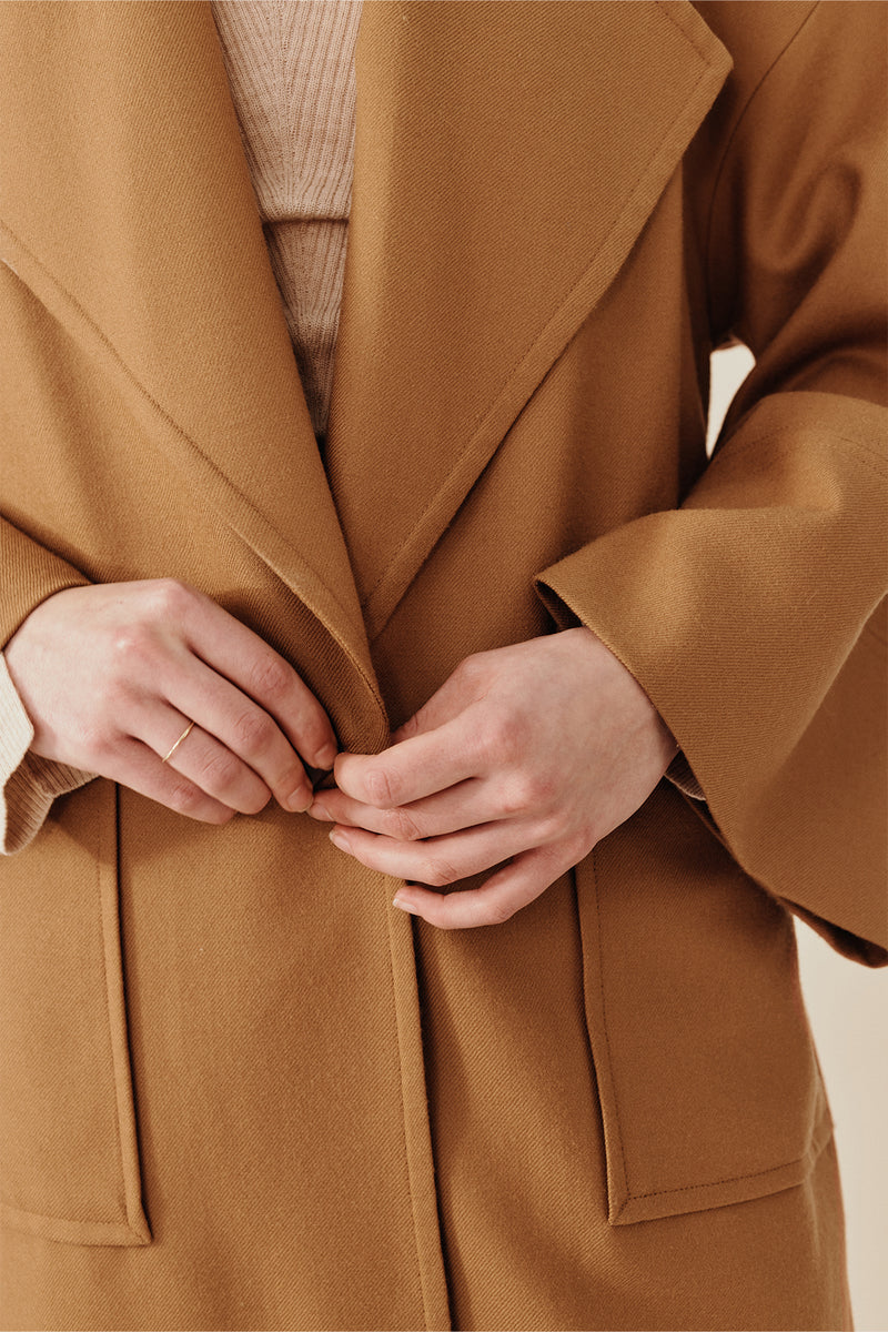 Model wearing Australian women’s fashion designer GINGER & SMARTS’ pure caramel wool Affinity Coat featuring relaxed fit, large lapels, patch pockets with dropped shoulders and wide sleeves. Worn with the Dimension Knit in oatmeal & cream Annie Jeans. 