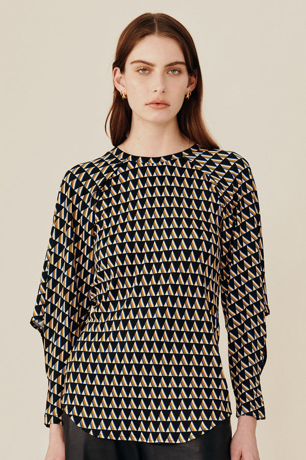 Australian luxury fashion designer GINGER & SMARTS' women's geometric printed silk long sleeve top with a crew neck and angular sleeve. Worn on a model with the women's black Genesis Leather Pant