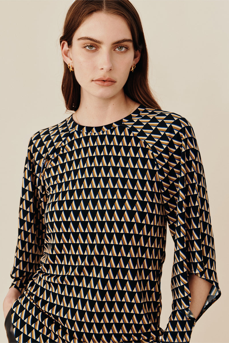 Australian luxury fashion designer GINGER & SMARTS' women's geometric printed silk long sleeve top with a crew neck and angular sleeve. Worn on a model with the women's black Genesis Leather Pant