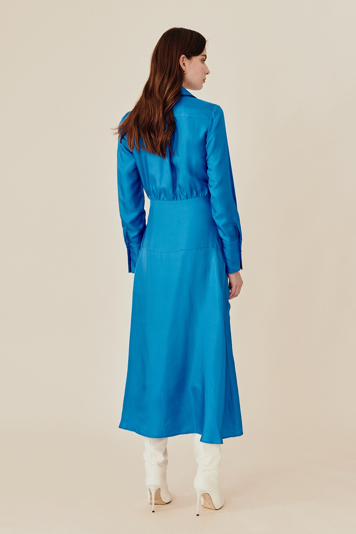 back view of Model wearing Australian fashion designer GINGER & SMARTS' blue silk Libertine that is the classic wrap silhouette that features a sharp collar and gently flared skirt with a long shirt sleeve.  