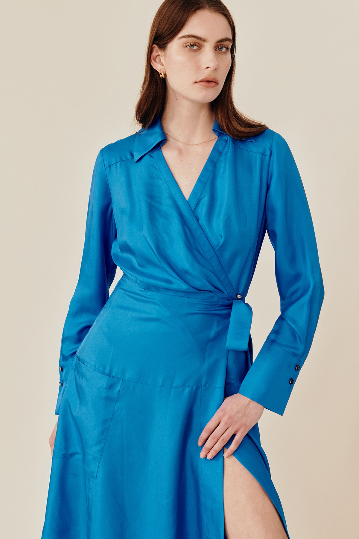 Model wearing Australian fashion designer GINGER & SMARTS' blue silk Libertine that is the classic wrap silhouette that features a sharp collar and gently flared skirt with a long shirt sleeve.  