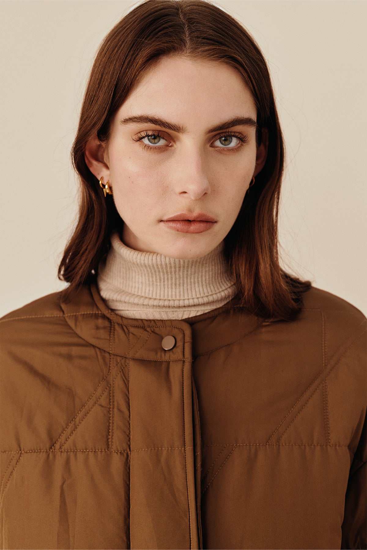 Model wearing the Australian luxury fashion designer GINGER & SMARTS' brown Sterling Quilted Coat featuring quilt detailing, lightweight design and is knee length.Worn with the women's black Genesis Leather Pant and Oatmeal Dimension Knit