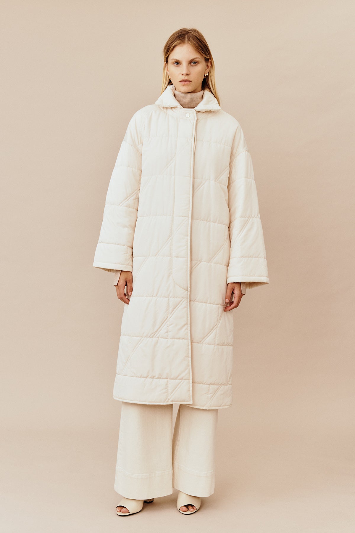 Model wearing the Australian luxury fashion designer GINGER & SMARTS' cream Sterling Quilted Coat featuring quilt detailing, lightweight design and is knee length.