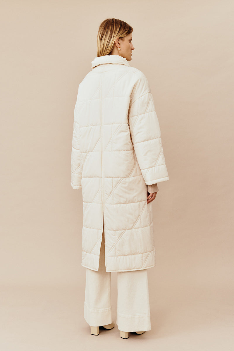 Back view of model wearing the Australian luxury fashion designer GINGER & SMARTS' cream Sterling Quilted Coat featuring quilt detailing, lightweight design and is knee length. Worn with the wide leg cream Annie Jeans.