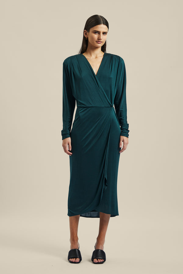 Model wearing the green forest silk Coalesce Wrap Dress from Ginger & Smart featuring a waist tie with a v-neckline and midi length.