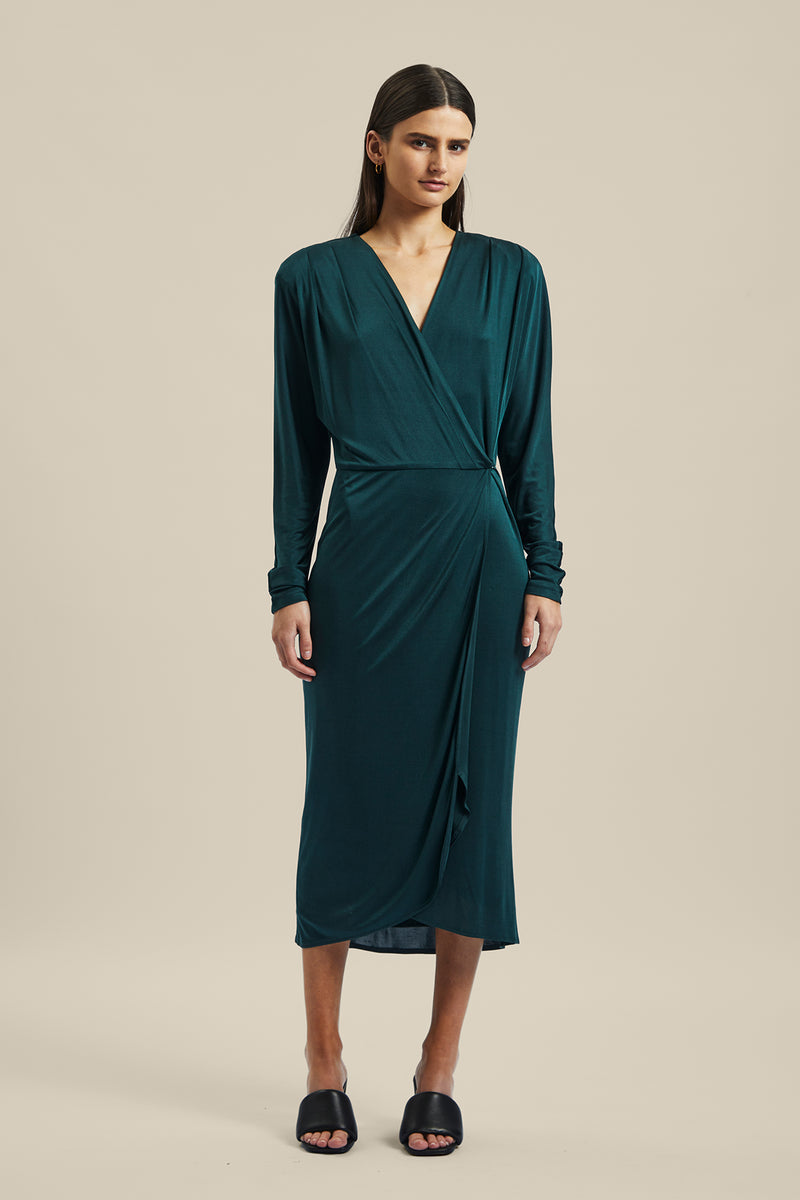 Model wearing the green forest silk Coalesce Wrap Dress from Ginger & Smart featuring a waist tie with a v-neckline and midi length.