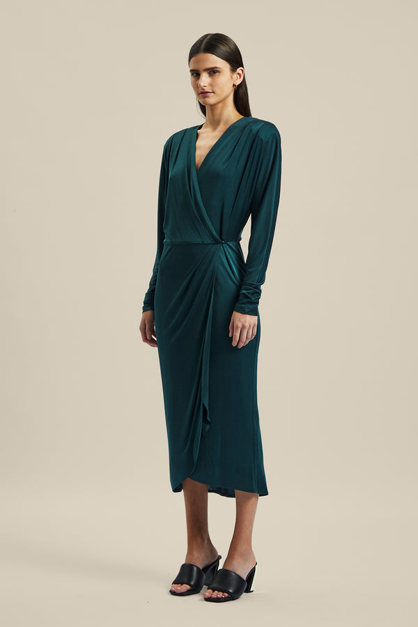 Model wearing the green forest silk Coalesce Wrap Dress from Ginger & Smart featuring a waist tie with a v-neckline and midi length.