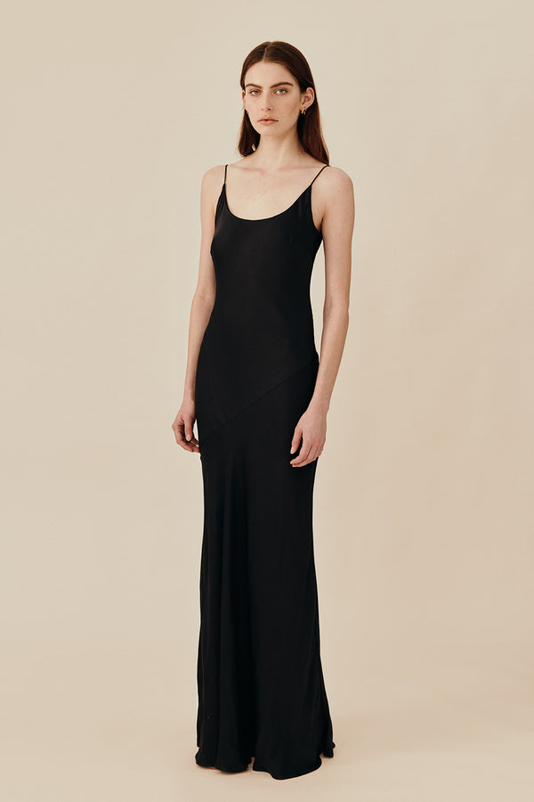 Model wearing 90’s inspired black Nocturnal Slip Dress from Australian luxury women’s designer GINGER & SMART, featuring body skimming fit, spaghetti straps, scoop neckline detail, maxi length, and a bias-cut skirt.