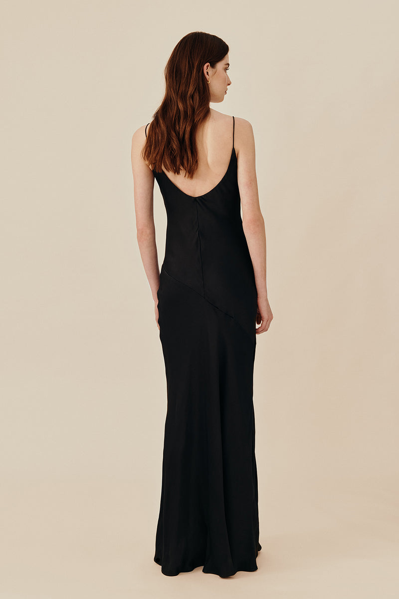 Back view of model wearing 90’s inspired black Nocturnal Slip Dress from Australian luxury women’s designer GINGER & SMART, featuring body skimming fit, spaghetti straps, scoop neckline detail, maxi length, and a bias-cut skirt.