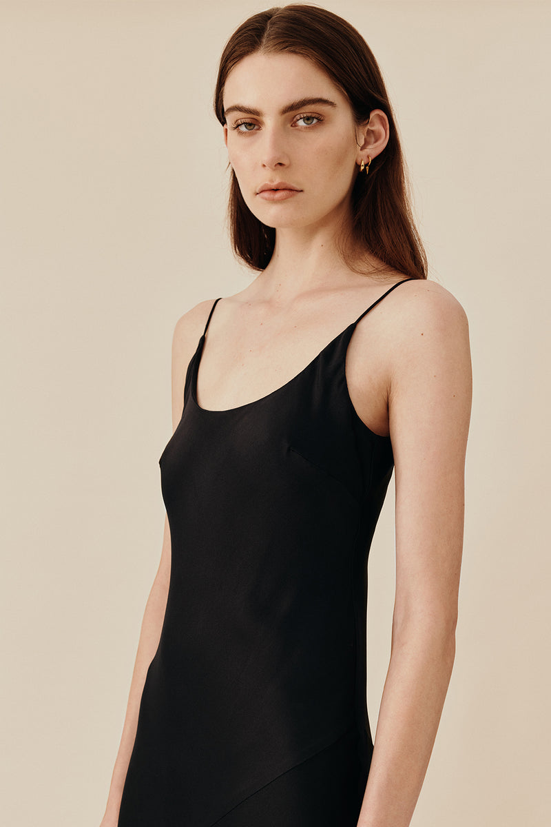 Model wearing 90’s inspired black Nocturnal Slip Dress from Australian luxury women’s designer GINGER & SMART, featuring body skimming fit, spaghetti straps, scoop neckline detail, maxi length, and a bias-cut skirt.