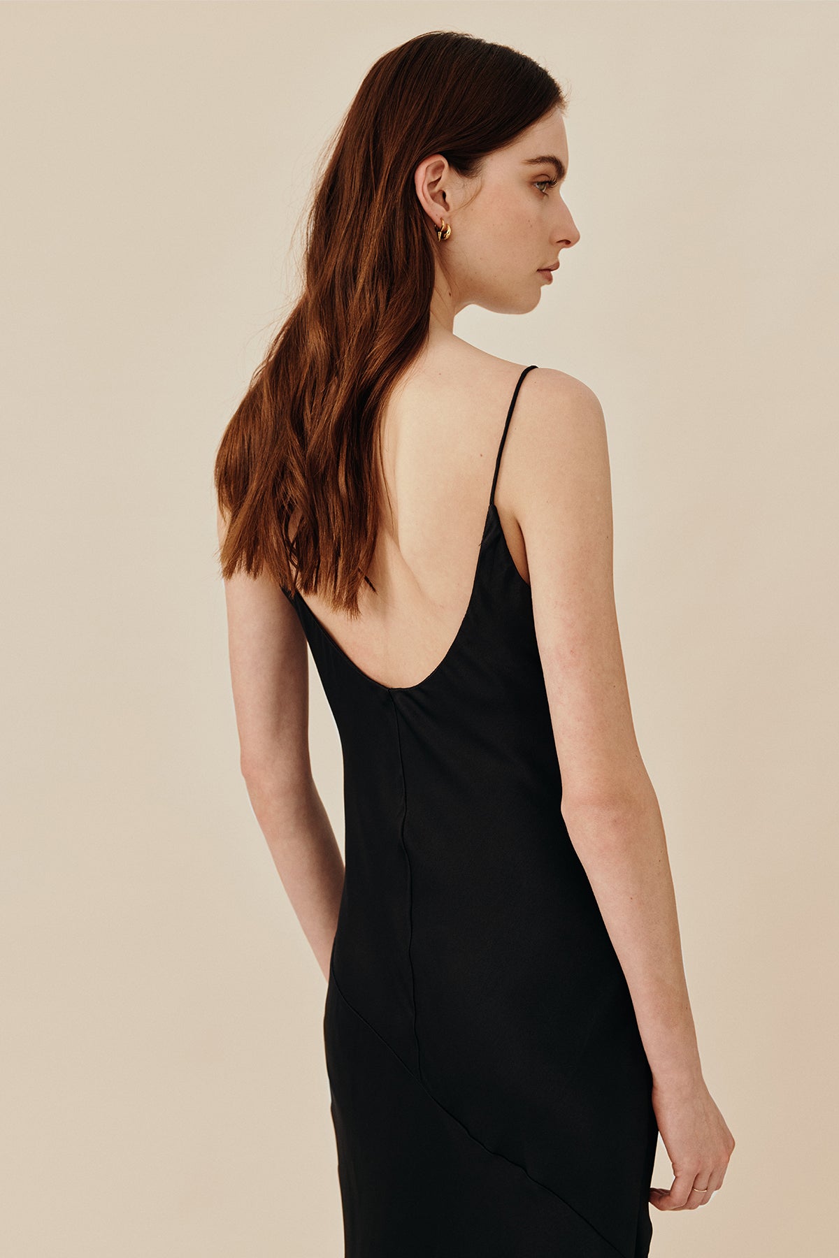 Model wearing 90’s inspired black Nocturnal Slip Dress from Australian luxury women’s designer GINGER & SMART, featuring body skimming fit, spaghetti straps, scoop neckline detail, maxi length, and a bias-cut skirt.