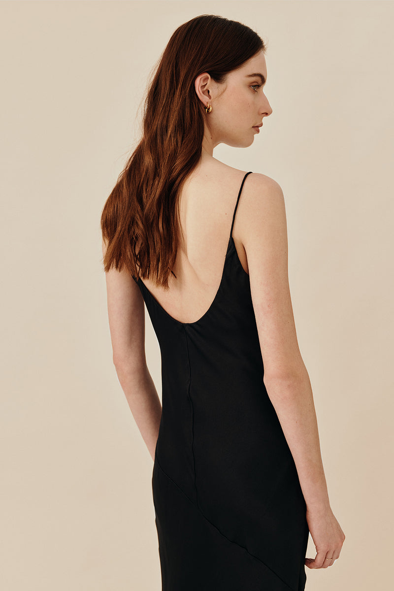 Model wearing 90’s inspired black Nocturnal Slip Dress from Australian luxury women’s designer GINGER & SMART, featuring body skimming fit, spaghetti straps, scoop neckline detail, maxi length, and a bias-cut skirt.