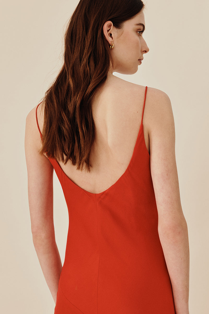 Back view of model wearing 90’s inspired red Nocturnal Slip Dress from Australian luxury women’s designer GINGER & SMART, featuring body skimming fit, spaghetti straps, scoop neckline detail, maxi length, and a bias-cut skirt.