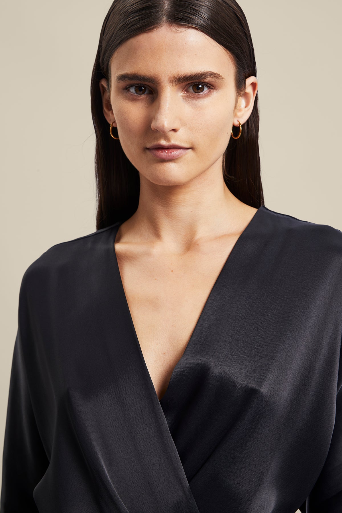 Model wearing black Nocturnal Wrap Dress from Australian luxury designer GINGER & SMART, featuring , long sleeves with wrist cuffs, waist tie, V neckline, midi length with bias cut asymmetrical hemline.
