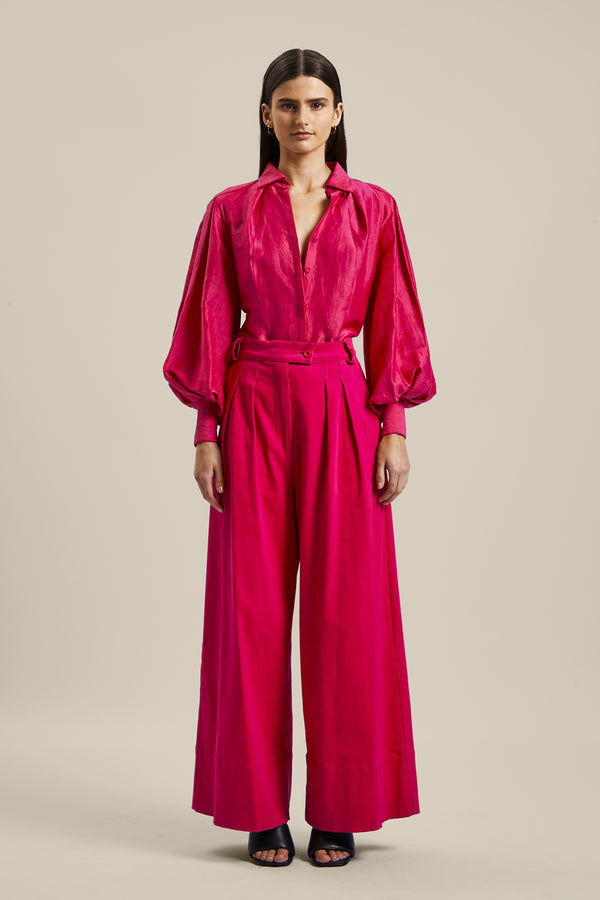 Model wearing the Novelist Pant from Australian women’s designer GINGER & SMART featuring a wide leg and sharp tailoring. Worn with a pink blouse.